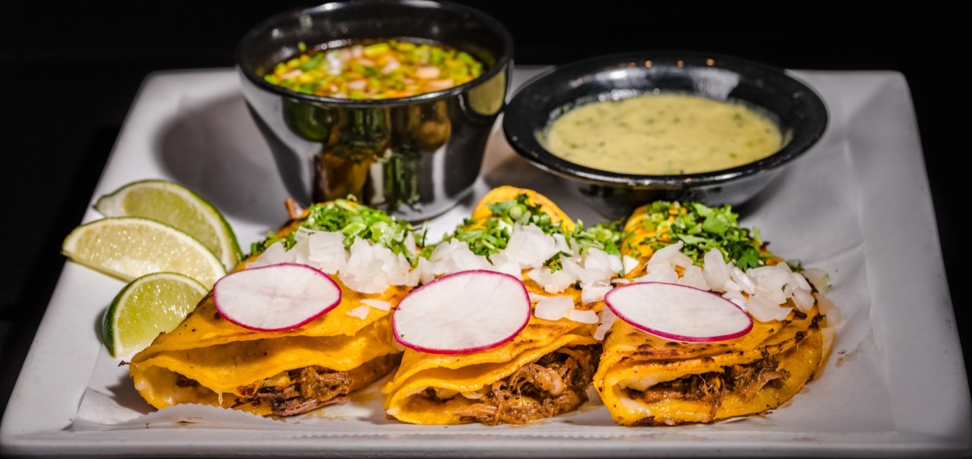 Three quesabirria tacos with consommé and salsa verde