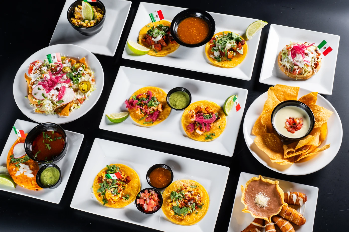 Happy hour plates from above: tacos, nachos, chips and queso, and platanitos